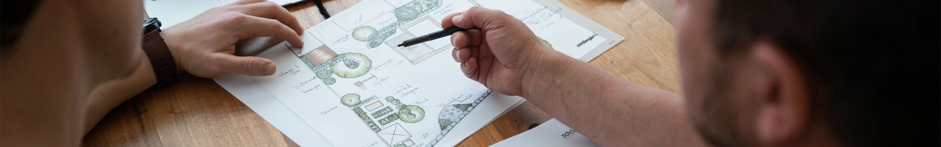 Planungsentwurf Gartengestaltung am Tisch zwischen zwei Männern